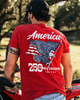 Person wearing a red t-shirt with an eagle and flag design, standing outdoors.