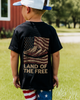 Child wearing a black t-shirt with an American flag design and 'Land of the Free' text, standing outdoors.