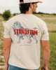 Man wearing a t-shirt with a lion graphic and 'STAND FIRM' text in an outdoor setting