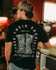 Man wearing a black t-shirt with text and graphic design in a kitchen setting