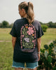Person wearing a black t-shirt with floral design and text in an outdoor setting