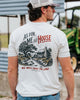 Man wearing a t-shirt with a graphic design and text, standing outdoors.