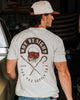 Man wearing a t-shirt with a graphic design and text, standing in an indoor setting.