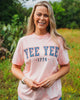 Woman wearing a pink t-shirt with 'YEE YEE 1776' text in a field